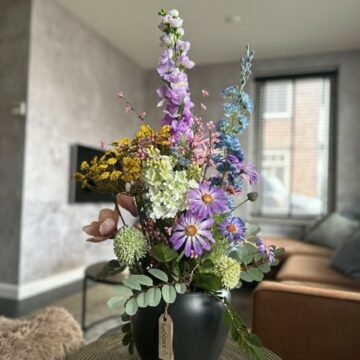 Schwarze breite Vase mit künstlichen Blumen in verschiedenen Farben